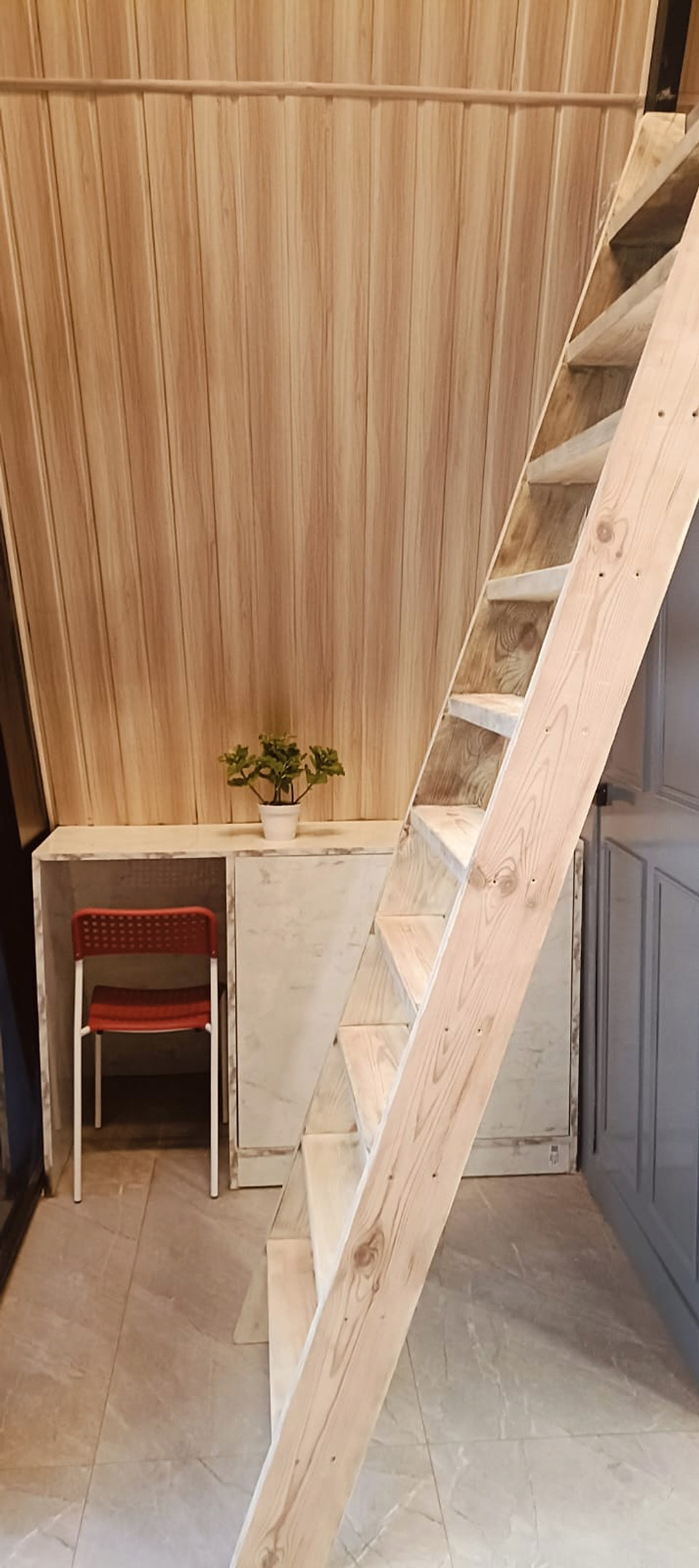 Wooden loft staircase beside a compact workspace
